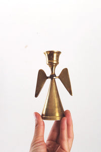 May include: A gold metal angel candle holder with a cone-shaped base and two wings.